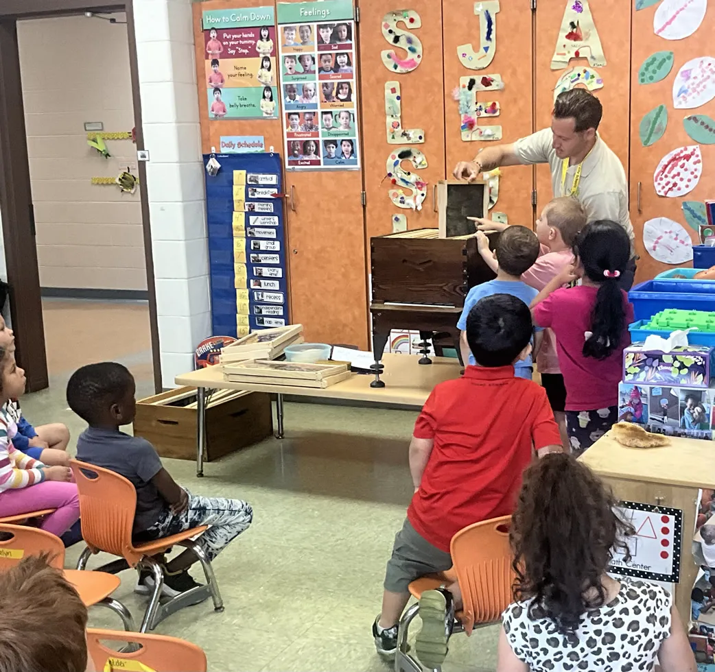 Students gathered around an observation beehive during a classroom pollinator workshop