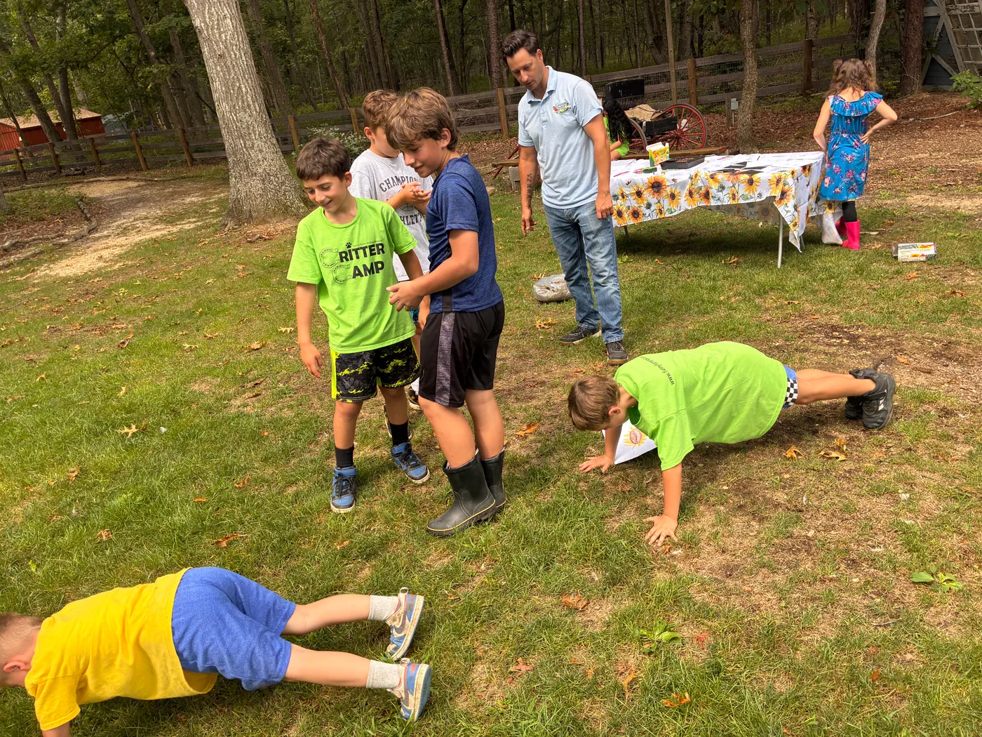 Critter Camp kids doing pushups on the grass with Don Grasso standing alongside
