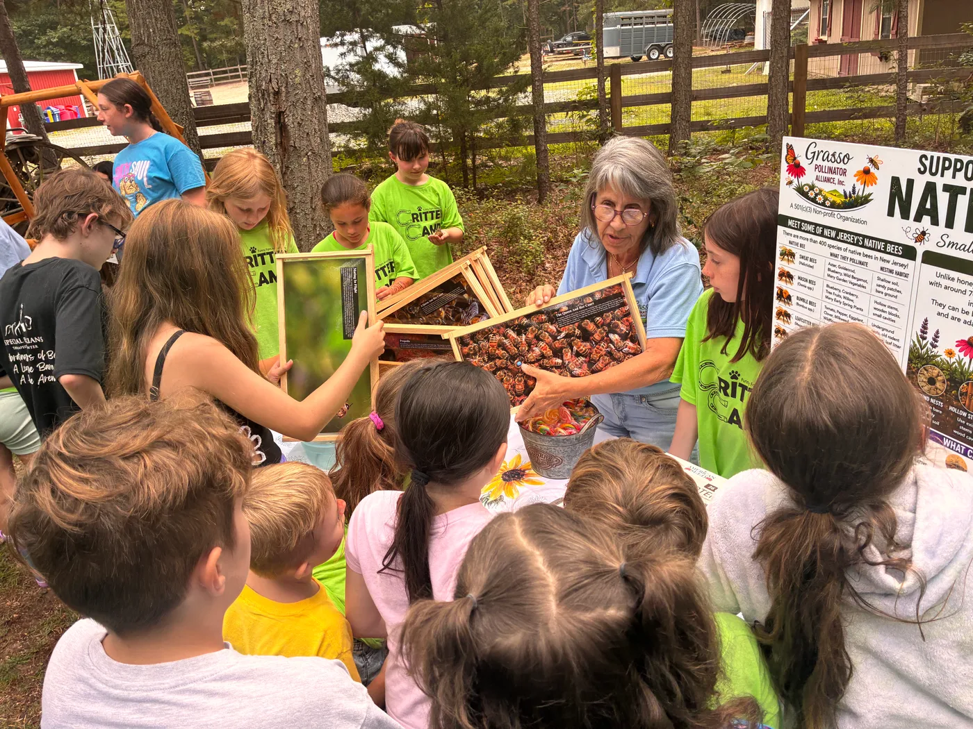 Critter Camp children crowding around a volunteer holding up a frame of honeycomb