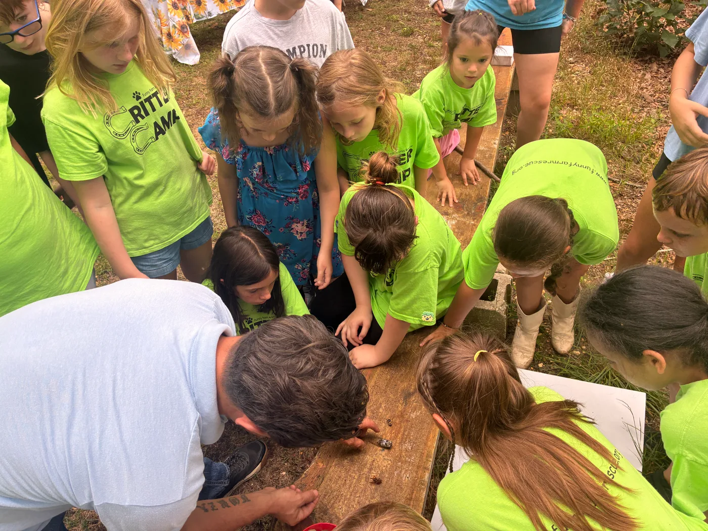 Children gathered around a table with their hands in loose soil